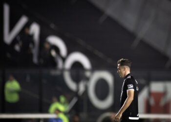 Jogador do Vasco pensativo em campo à noite.
