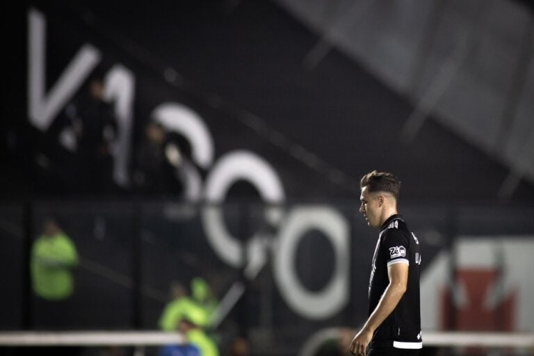 Jogador do Vasco pensativo em campo à noite.