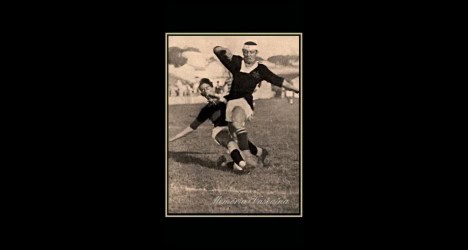Jogador de futebol em ação com a bola no campo.