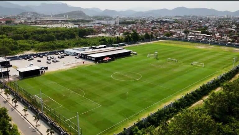 Estádio de futebol no subúrbio, com gramado bem cuidado.
