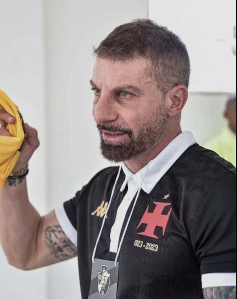 Homem com camiseta do Vasco, segurando roupa amarela.