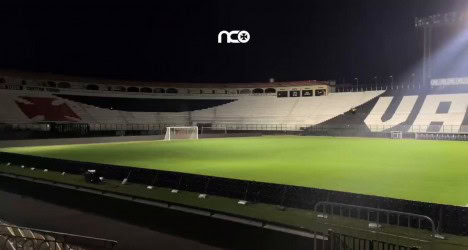Estádio do Vasco da Gama, iluminação noturna, gramado bem cuidado, arquibancadas vazias, ambiente preparado para jogo, ambiente esportivo, estádio com clima de expectativa.