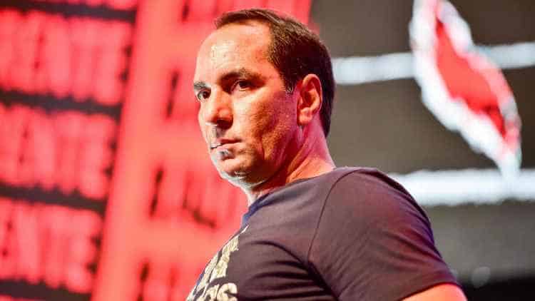 Homem com expressão séria, fundo vermelho vibrante.