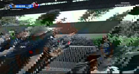 Homem conversando com torcedor, cercado por fãs.