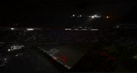 Estádio do Vasco iluminado e quase vazio sob o céu escuro.
