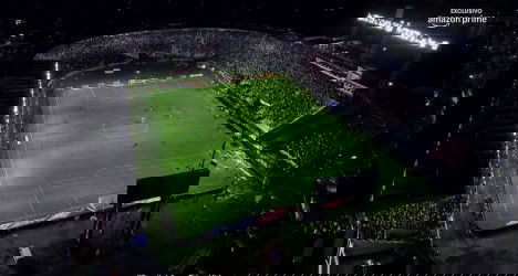 Estádio do Vasco à noite, cheio de torcedores e iluminação intensa, mostrando arquibancadas e o campo de futebol.