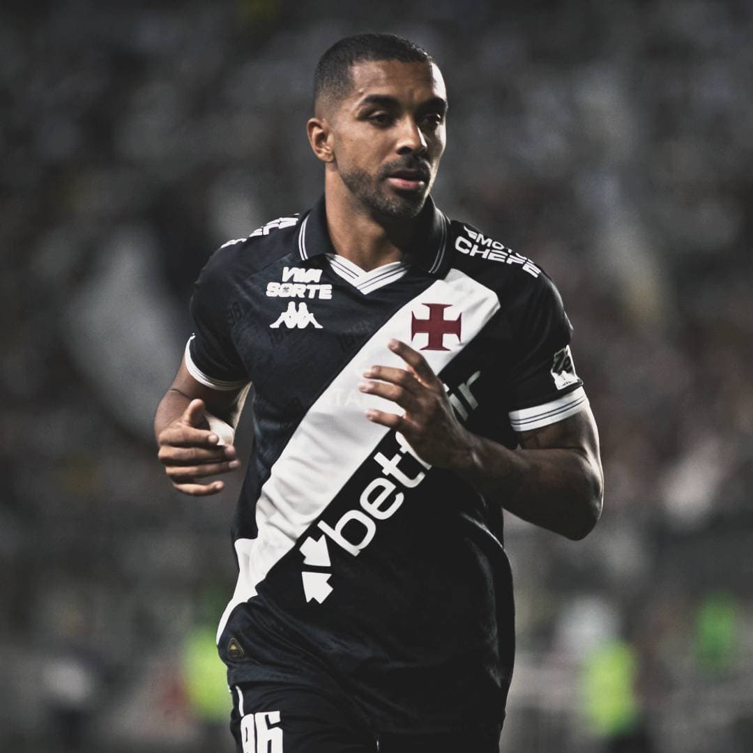 Atleta com uniforme do Vasco durante jogo, em movimento, fundo desfocado.