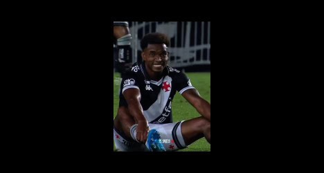Jogador do Vasco celebrando uma conquista em campo, sorridente, com uniforme do time e estádio ao fundo.