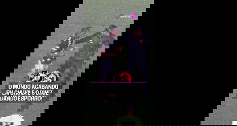 Jogadores em campo sob chuva intensa, comemorando juntos.