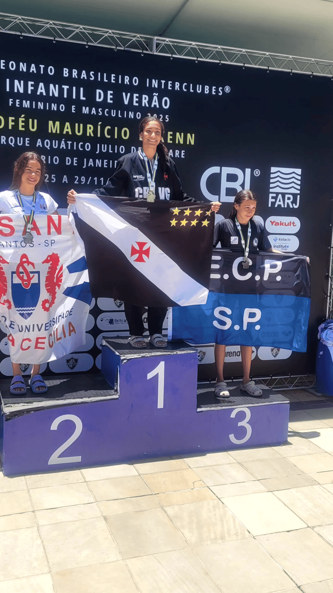 2. Alt: Atletas femininas com medalhas, na cerimônia de premiação.