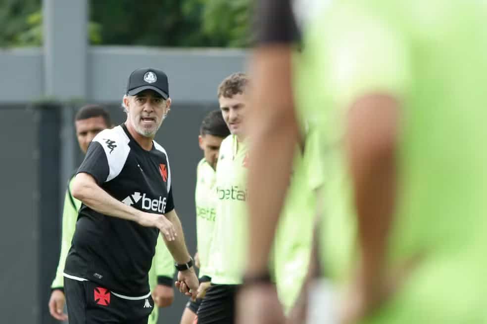 Treinador do Vasco orientando jogadores durante treino no campo de futebol.