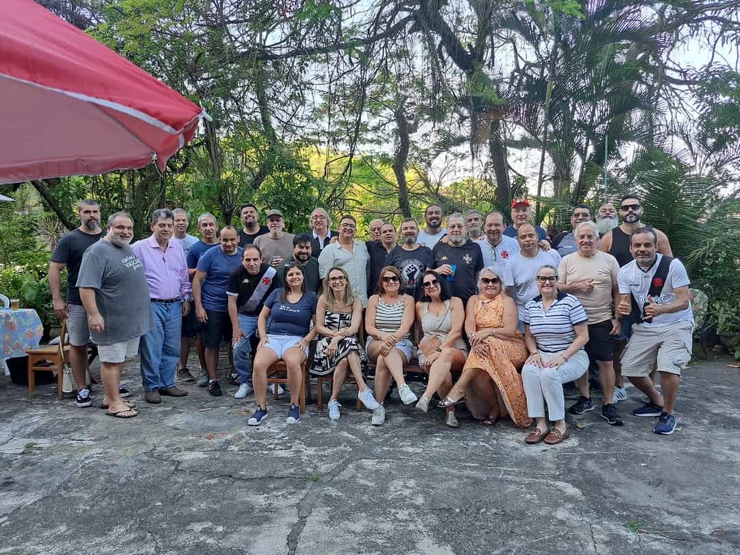 Grupo de pessoas em ambiente externo com árvores ao fundo.