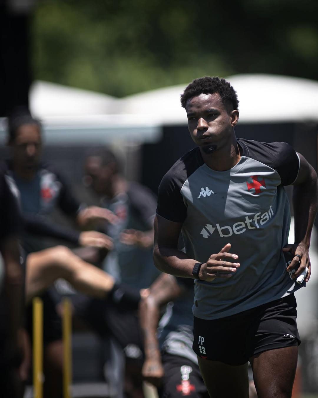 Jovem atleta do Vasco correndo em campo de treinamento ao ar livre.