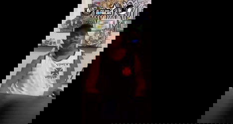 Homem usando camisa do Vasco sentado à mesa.