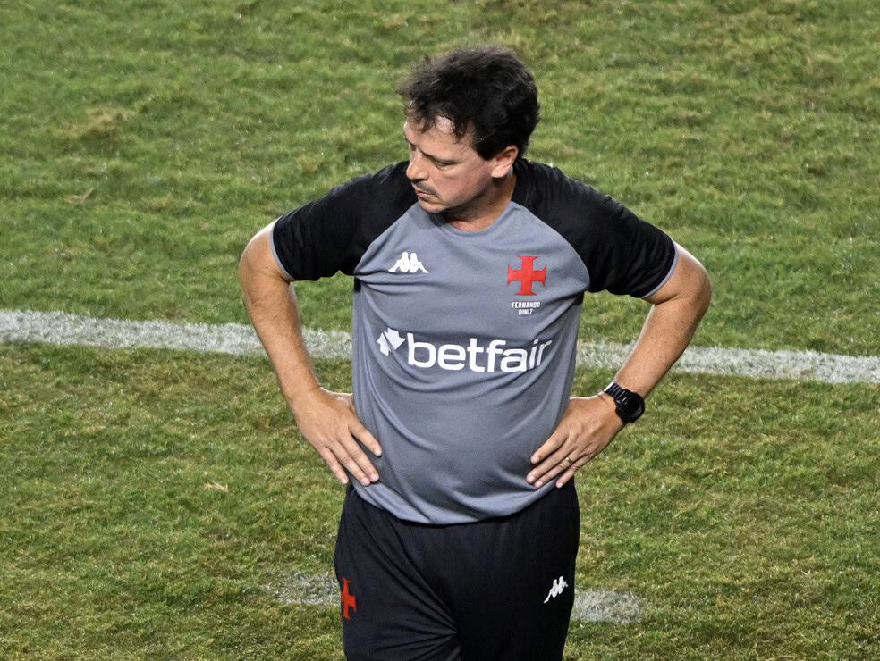 Treinador está pensativo, usando uniforme do Vasco.