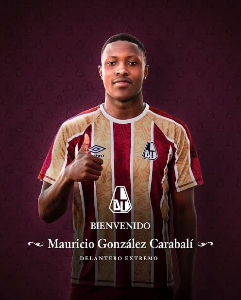 Jogador do Vasco com uniforme oficial, mostrando o escudo e detalhes do time em fundo roxo.