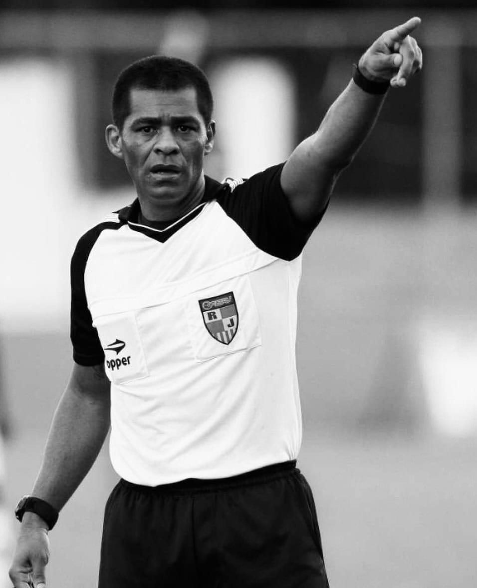 Árbitro de futebol em ação, sinalizando, uniforme esportivo.