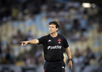 Arbitragem do Vasco em campo com torcida ao fundo.