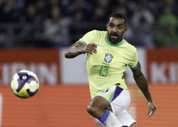 Jogador de futebol em ação com a camisa da seleção brasileira.