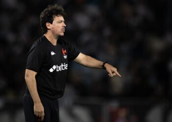 Imagem de homem técnico de futebol vestindo camisa preta, apontando com o braço estendido.