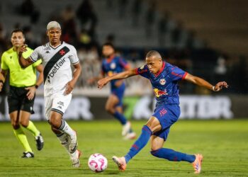 Jogador do Vasco chutando a bola em campo.