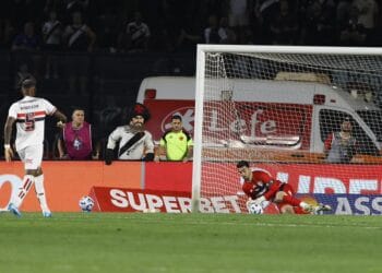 Bola entrando no gol durante jogo de futebol adulto.