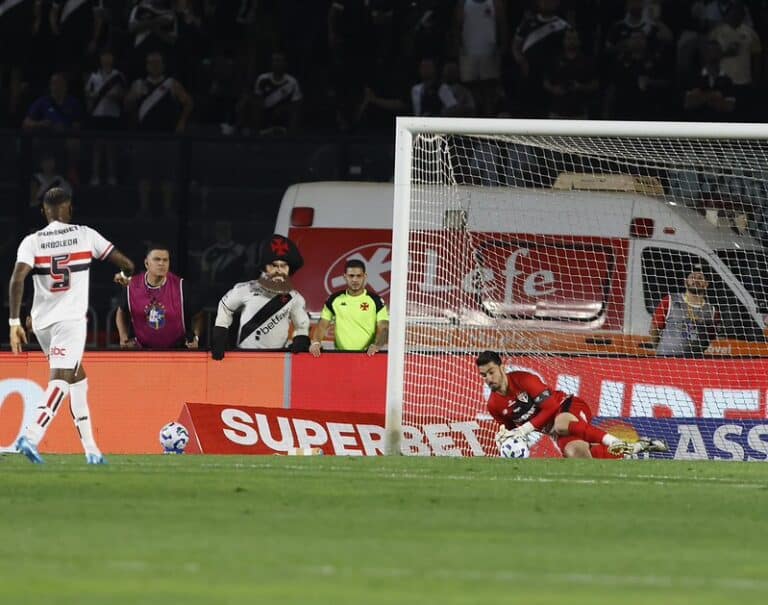 Bola entrando no gol durante jogo de futebol adulto.