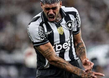 Bola de futebol com jogador do Vasco em ação.