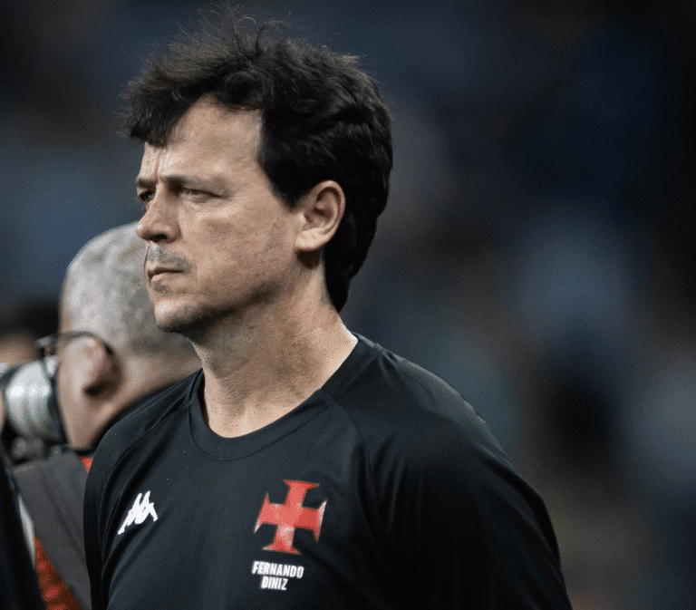 Homem de cabelo escuro, expressão séria, vestindo camiseta do Vasco.