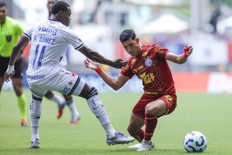Lutador com bola durante jogo de futebol no estádio.