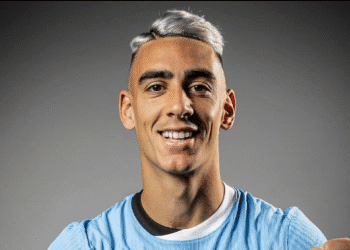 Jogador do Vasco sorrindo com uniforme azul.