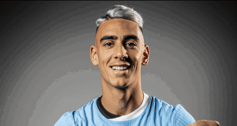 Jogador do Vasco sorrindo com uniforme azul.