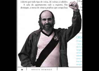 Homem com cabelo e barba escuros, usando jaqueta preta sobre camisa branca.