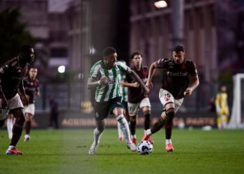 Jogo de futebol entre Vasco e adversários em campo iluminado.