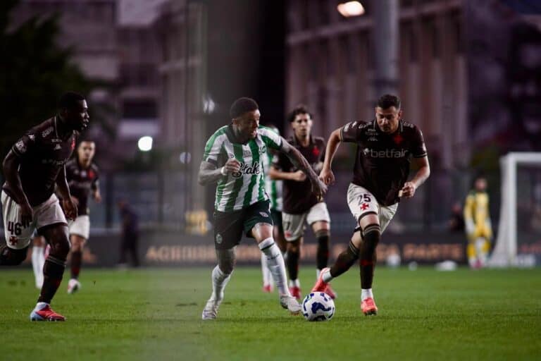 Jogo de futebol entre Vasco e adversários em campo iluminado.