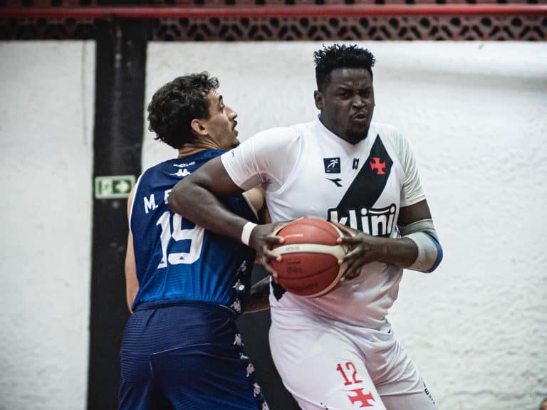 Atleta de basquete com bola em mãos, em disputa.