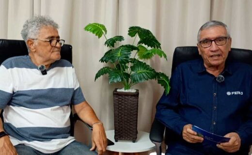 Homens conversando em ambiente interno com planta ao centro.