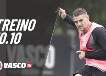 Futebolista treinando com colete rosa em campo.