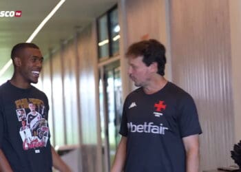 Jogador do Vasco sorrindo com treinador em corredor.