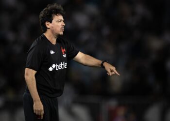 Arbitragem vestindo uniforme preto, apontando no campo.